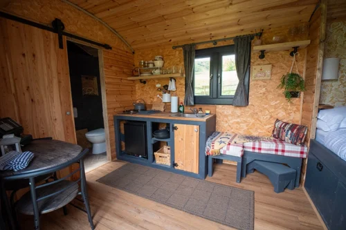 The Nook Shepherd Hut - Interior view of the table, kitchen area and seating