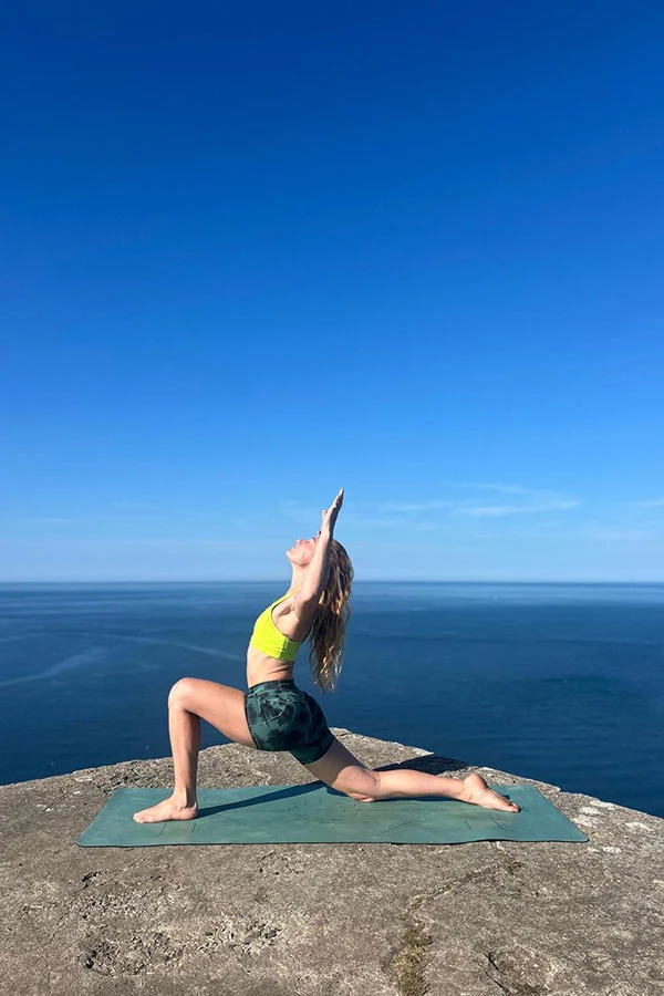 Yoga instructor April Rosson performing yoga on a cliff above the sea