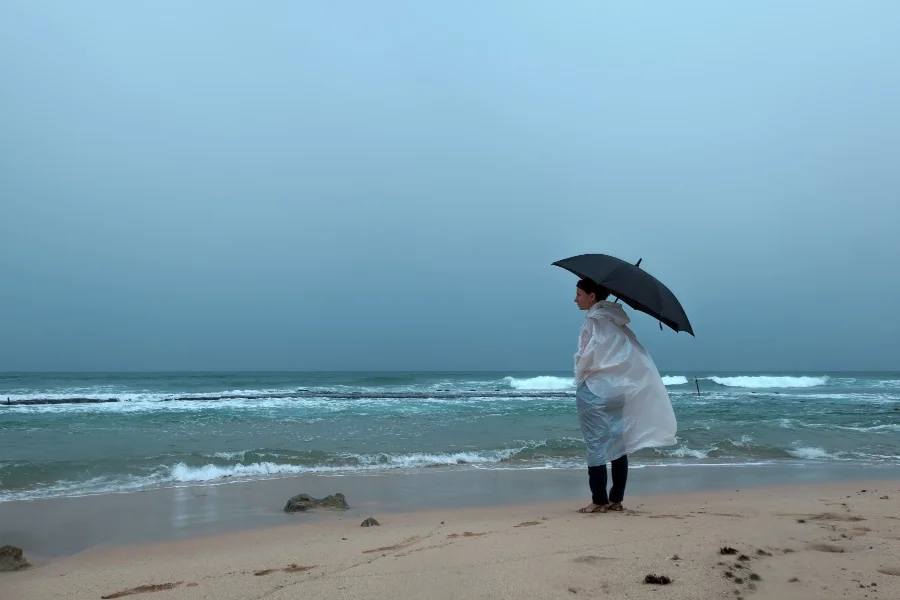 A woman standing on a beach in rainy weather